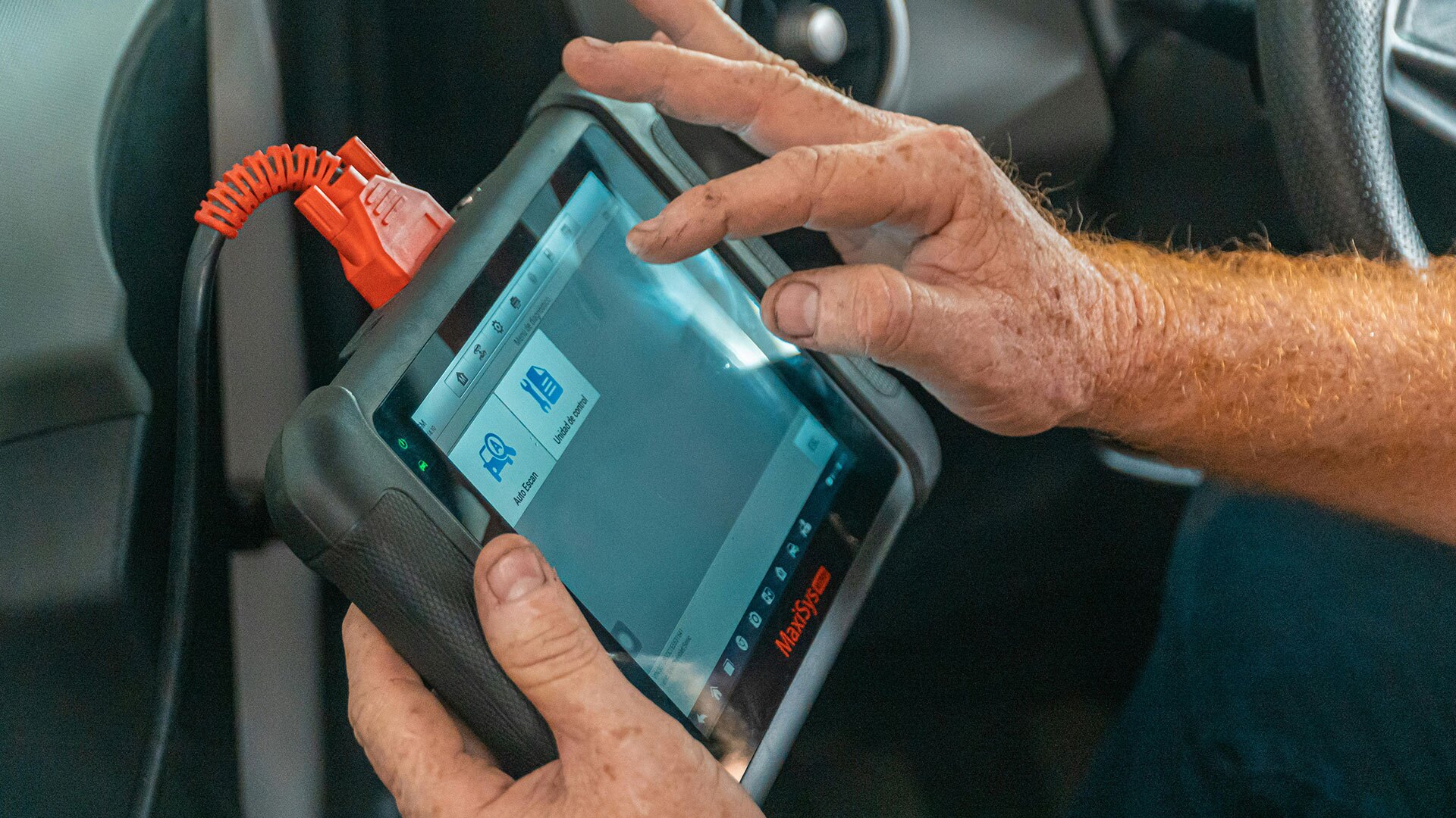 A close up of a plugged-in tablet giving car diagnostic reading to the person holding it.